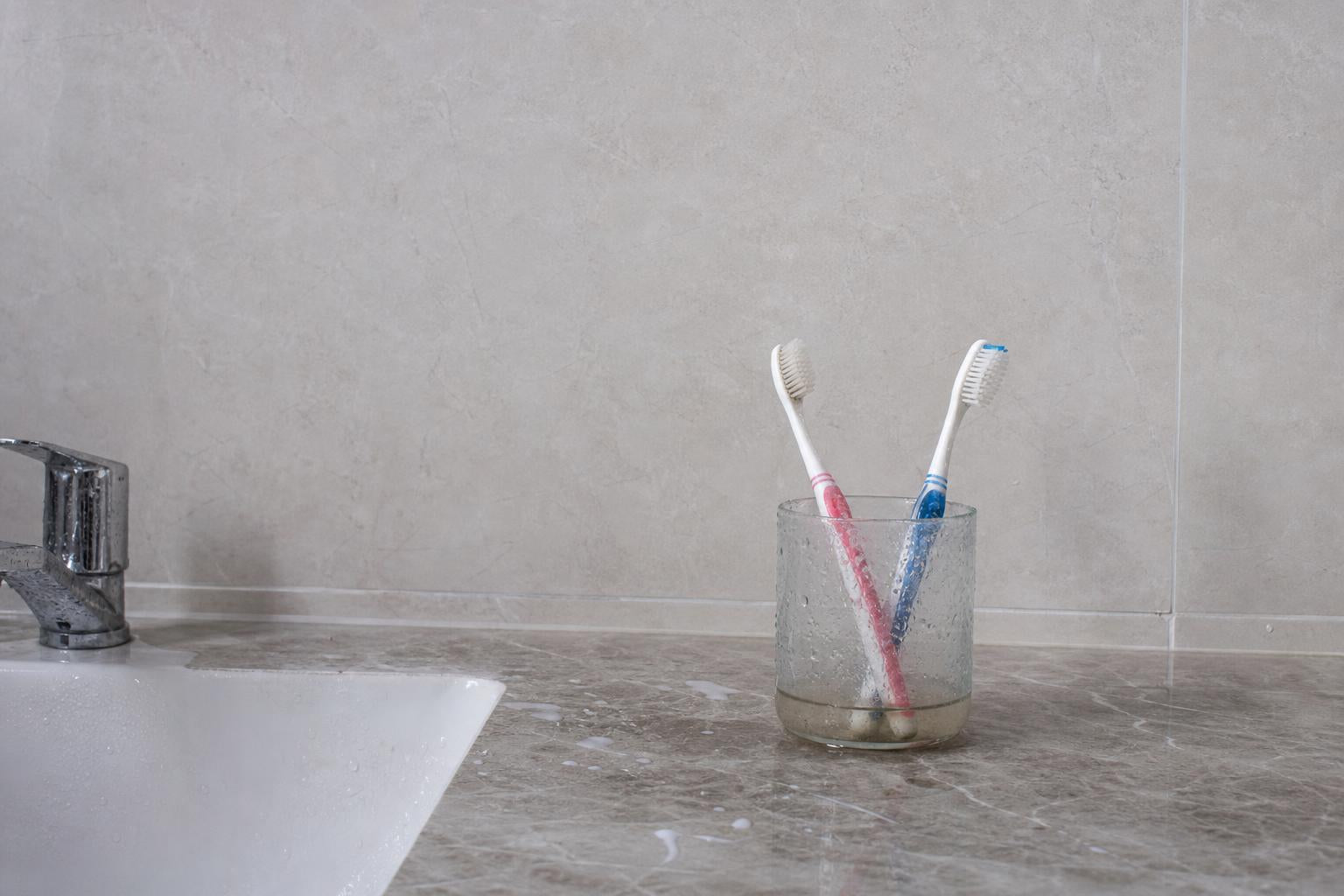 Toothbrushes in a wet cup on the sink